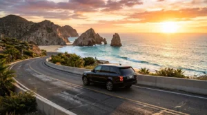 Luxury SUV driving on a scenic coastal highway in Los Cabos, Mexico, at sunset.